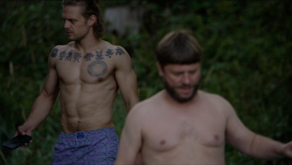 Seses film still from Locarno Film Festival. Two shirtless men in a scene from Drowning Dry.
