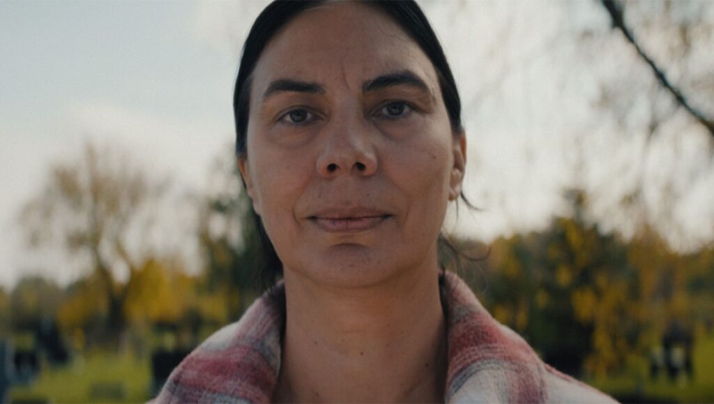 Close-up of a woman with dark hair and a plaid shirt. Nature background.