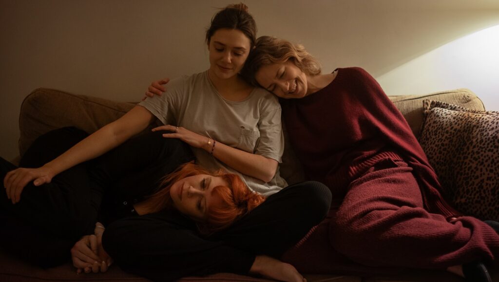 His Three Daughters movie scene: Three women on a couch, embracing. Family drama film.