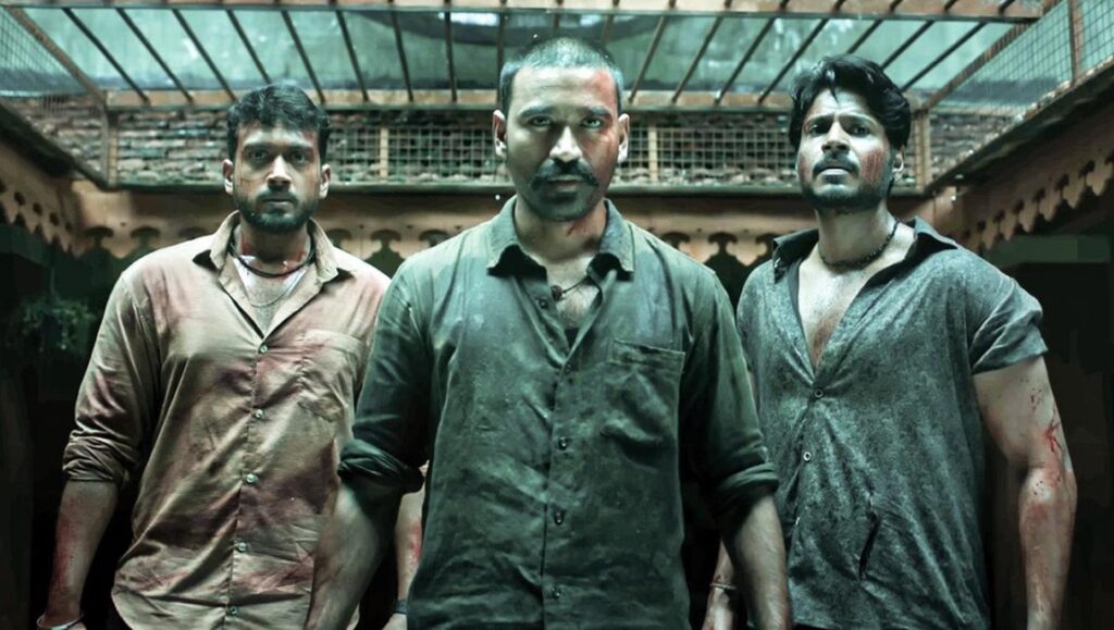 Dhanush in Raayan movie. Three men stand together, looking intense.