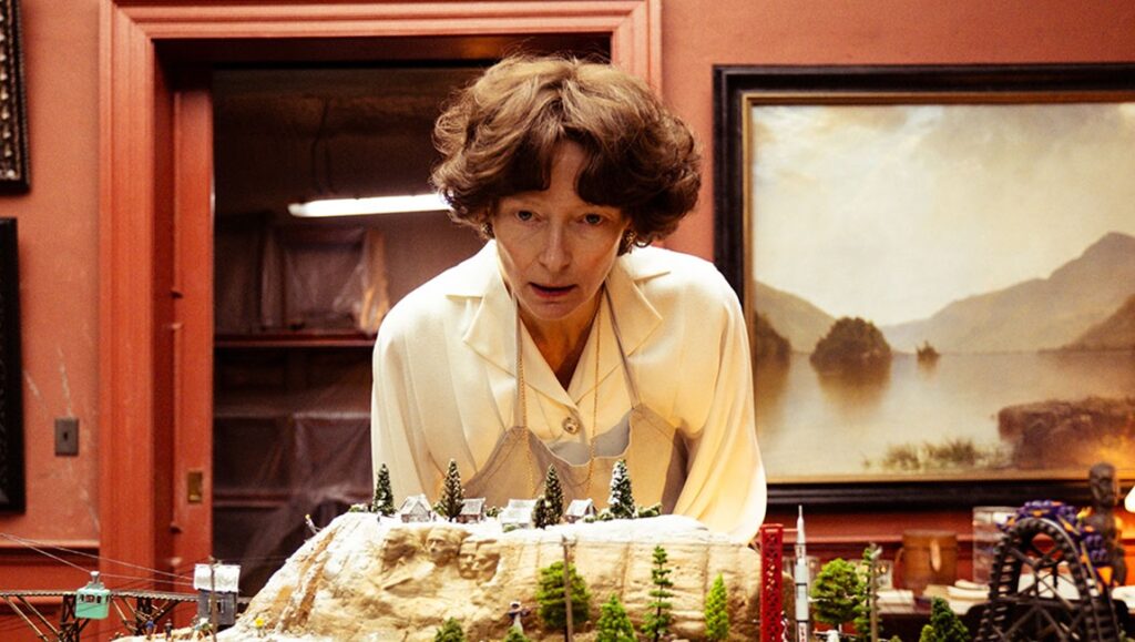 Tilda Swinton in Measures for a Funeral at TIFF '24. She looks at a miniature landscape. Movie review.
