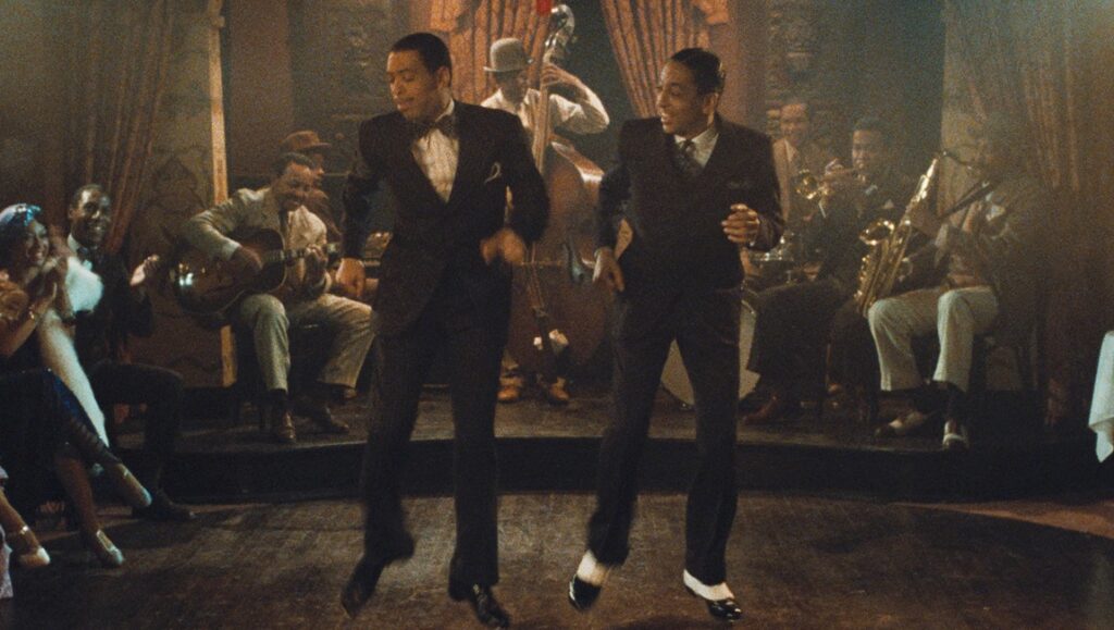 Scene from The Cotton Club, directed by Francis Ford Coppola. Two tap dancers perform with a jazz band on stage.