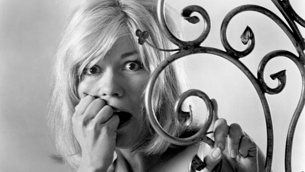 Dementia 13 — Francis Ford Coppola Black and white still from Dementia 13. Scared woman with hand to mouth. Horror film.