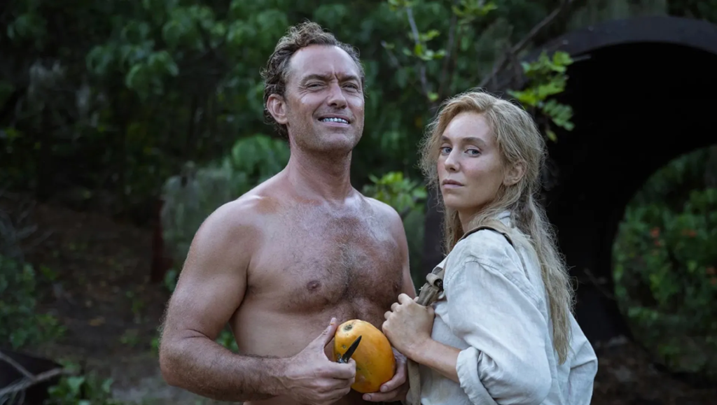 Jude Law and Ana de Armas in Eden at TIFF 2024. Law holds a fruit. De Armas wears a shirt.