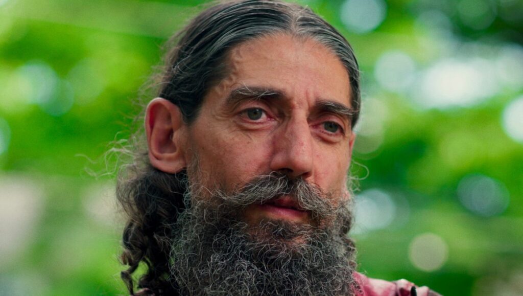 Christopher Jason Bell in Failed State review. Portrait of Mitch Blummer with long hair and beard.