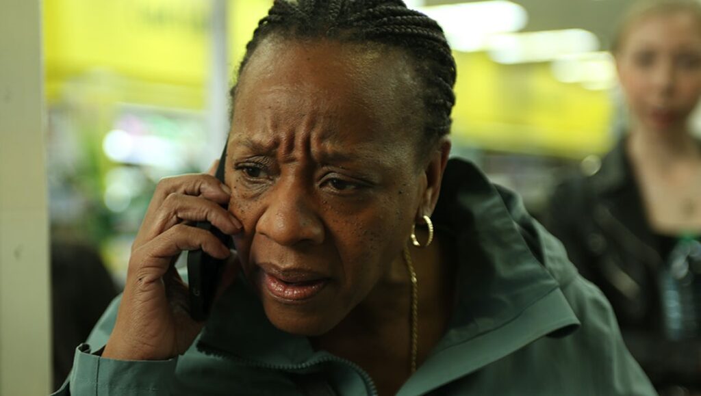 Measures for a Funeral film still. Woman with worried expression on phone. TIFF '24 review.