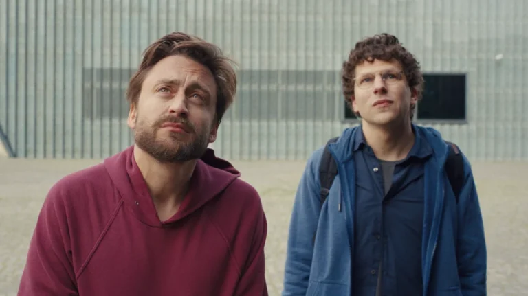 A Real Pain movie scene. Jesse Eisenberg and Kieran Culkin look upwards with curiosity. Film review.