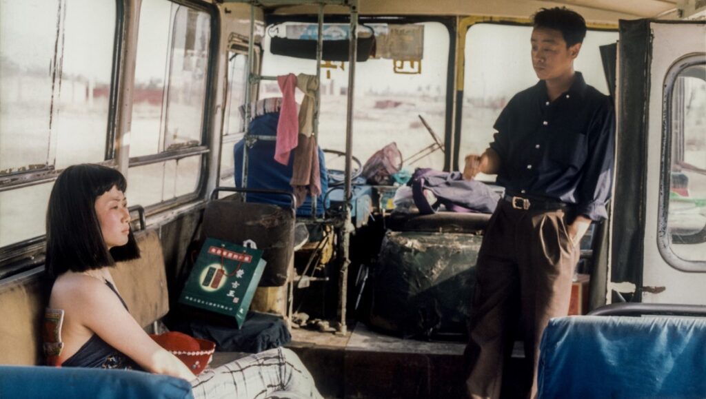 Caught by the Tides film still from NYFF 2024. Woman and man on bus, luggage.