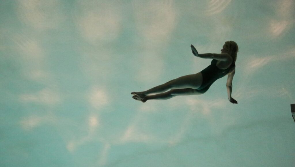 It's Not Me review: Woman in swimsuit appears to float underwater. Leos Carax film still.