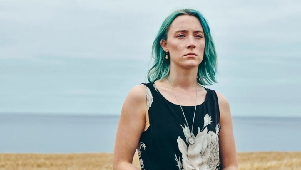 Saoirse Ronan in The Outrun movie review. Woman with teal hair on a windswept coast. Nora Fingscheidt film.