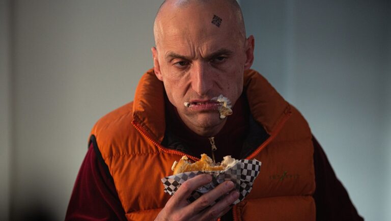 Alien 2: Bald man in orange vest eating a messy sandwich. PÖFF '24 film review.