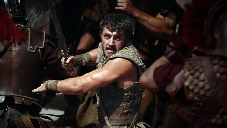 Gladiator II review. A warrior with a sword surrounded by Roman soldiers. Ridley Scott film.