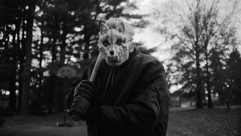 Hippo movie still: Man in wolf skull mask holds baseball bat in black and white.