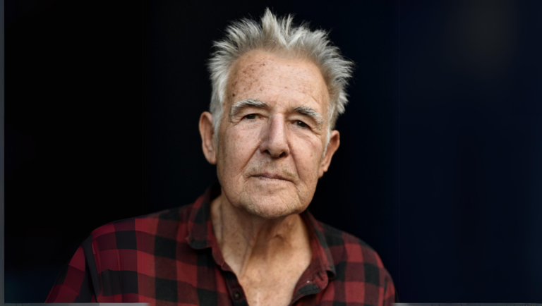 John Smith portrait. Interview with John Smith, author. Photo of John Smith in a red and black flannel shirt.