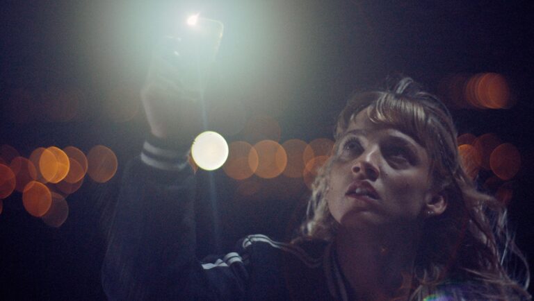 Meanwhile on Earth film scene: Woman with flashlight looking up at night. Jérémy Clapin movie review.