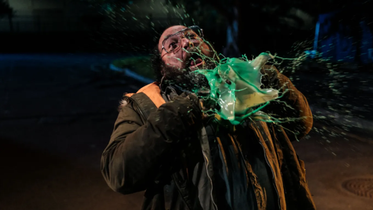 Street Trash movie scene: Man splattered with green liquid. Horror film review.