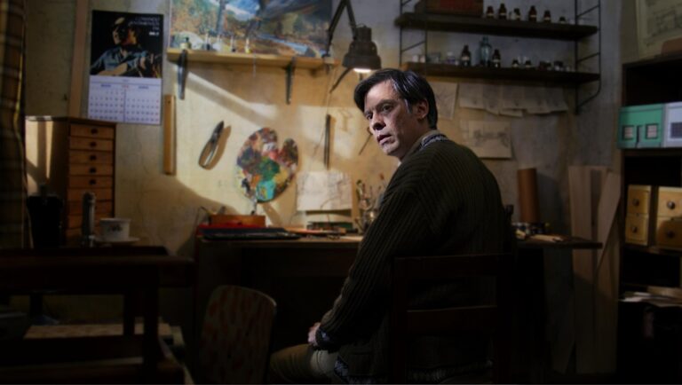 A Yard of Jackals film still. Artist in studio with palette, paints, and calendar. Tallinn Black Nights Film Festival.