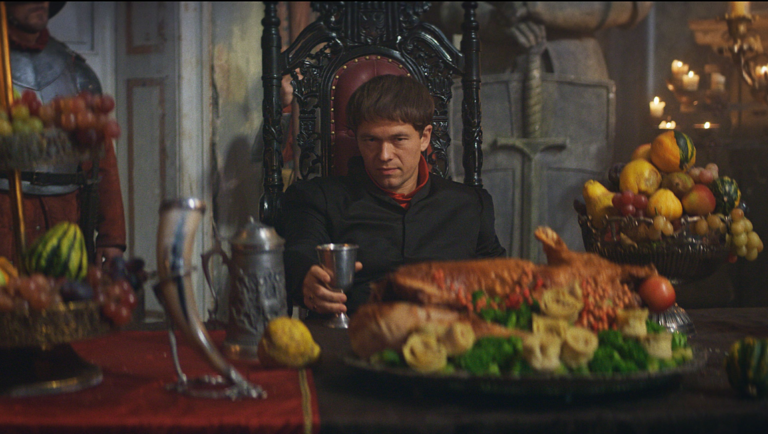 Stockholm Bloodbath scene: King sits on throne at a feast with roasted pig and fruit.