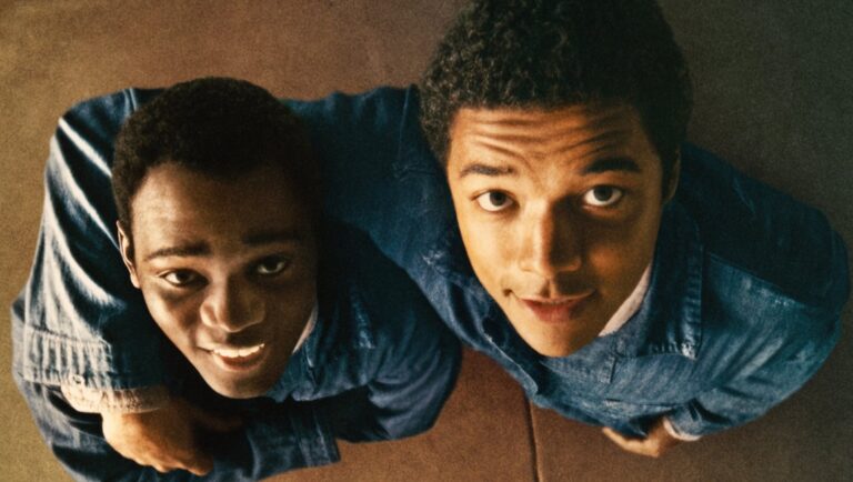 Film review of RaMell Ross's Nickel Boys. Two young Black men look up, wearing blue shirts.