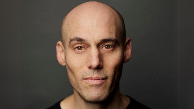 Close-up portrait of Joshua Oppenheimer. Interview with the documentary filmmaker.