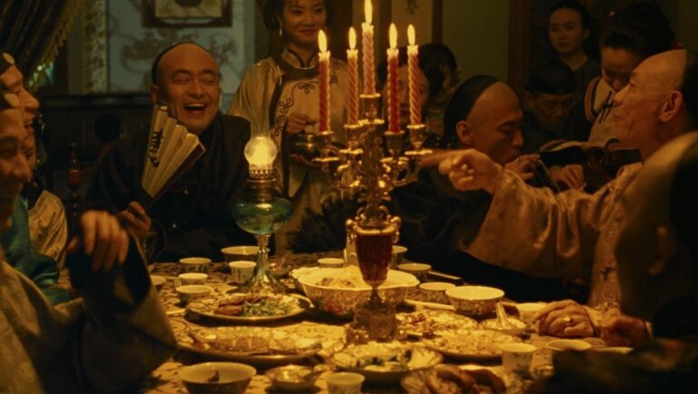 Shanghai Flowers film scene. People gathered around a table with food, candles, and an oil lamp.