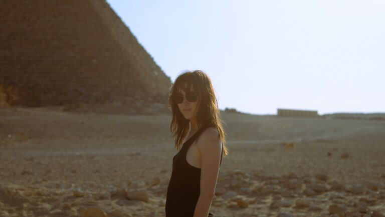 Woman in sunglasses near an Egyptian pyramid. Desert landscape, travel photography.