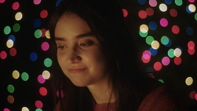 Young woman with dark hair in front of colorful bokeh lights. Portrait.