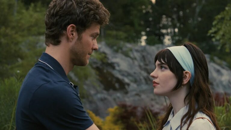 Companion movie still: Man and woman face each other outdoors. The woman wears a headband.