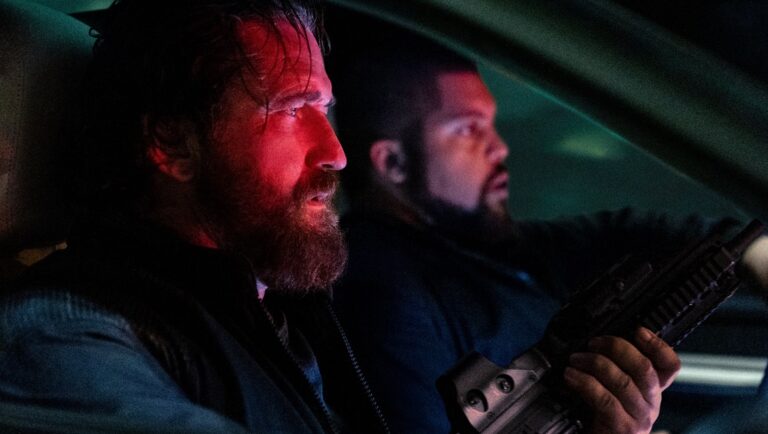 Den of Thieves movie scene. Gerard Butler in car, holding rifle. Action film.
