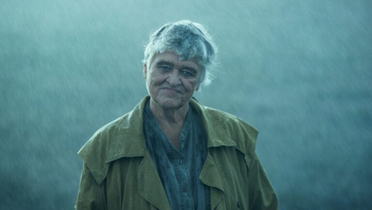 IFFR 2025 — Dispatch 1: Yasuko, Songs of Days Past, Ariel, Blind Love Portrait of an older woman in the rain. She wears a coat and smiles slightly. Weather, people, outdoors.