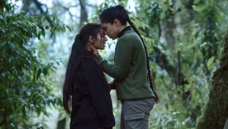 Film still from Bokshi movie. Two women embrace in a forest setting. Drama, emotion, connection.