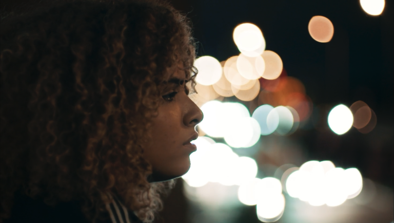 Still from Gamma Rays at Slamdance Film Festival. Woman in profile, night lights bokeh.