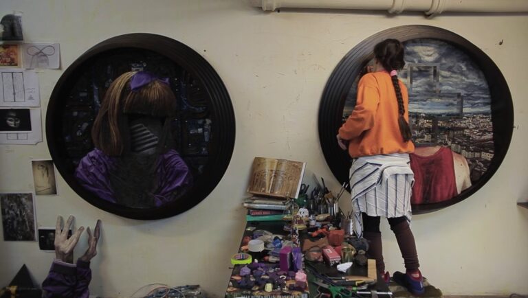 Doc Fortnight 2025 artwork: Two circular portraits, one of a doll and the other of a city, with an artist working on them.