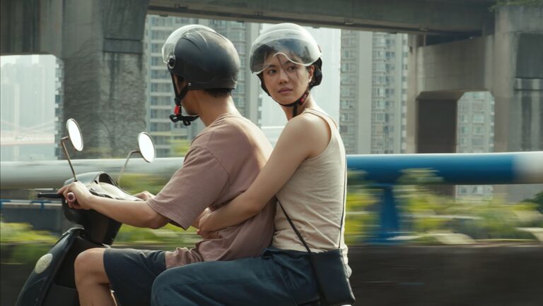 Couple riding a scooter with helmets in city. Asian woman hugs man driving. Travel and urban lifestyle.