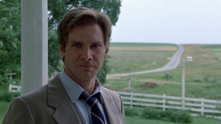 Harrison Ford in Witness. Detective John Book stands on a porch. Amish country background. Movie scene.