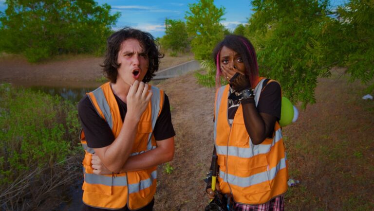 Rats 2025 film still. Two shocked people in safety vests outdoors. Horror movie scene. Sci-fi film.