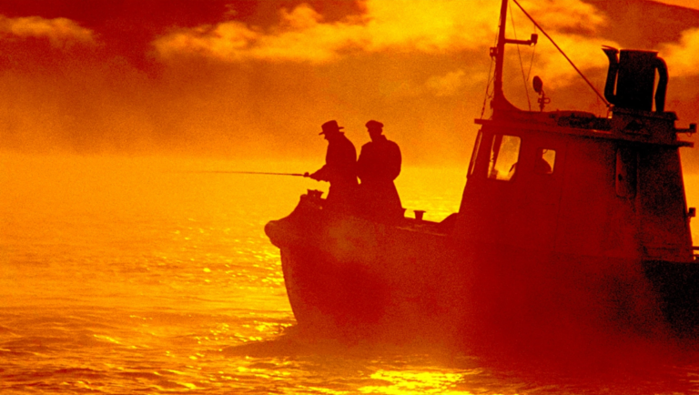Two fishermen on a boat at sunset. Fishing boat silhouette on golden water. Fishing scene.
