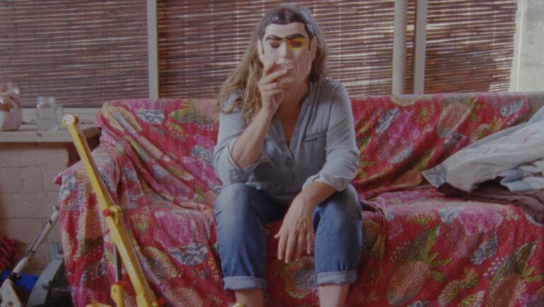 Woman in mask sits on sofa. Conceptual art photo by Lee-Anne Smith.