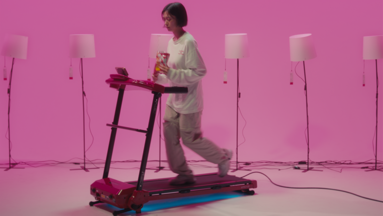 Woman on treadmill with chips. Pink background, lamps. Fitness, lifestyle.