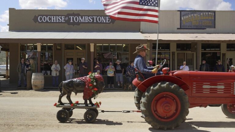 Doc Fortnight 2025: Man drives a red tractor with an American flag and a buffalo statue in tow in Cochise & Tombstone, Arizona.