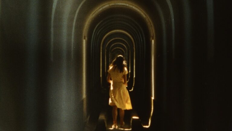 First Look 2025: Desert of Namibia, The Periphery of the Base, Zodiac Killer Project Woman walking through a tunnel. Arches and light create a sense of depth.