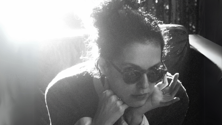 Dea Kulumbegashvili, film director. Black and white portrait of Dea with sunglasses, hands to face. Interview.