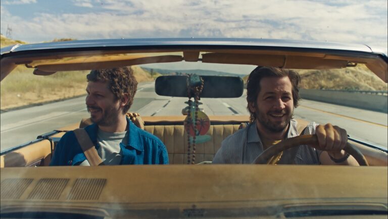 Two men smiling in a convertible car on a road trip. Travel and adventure.