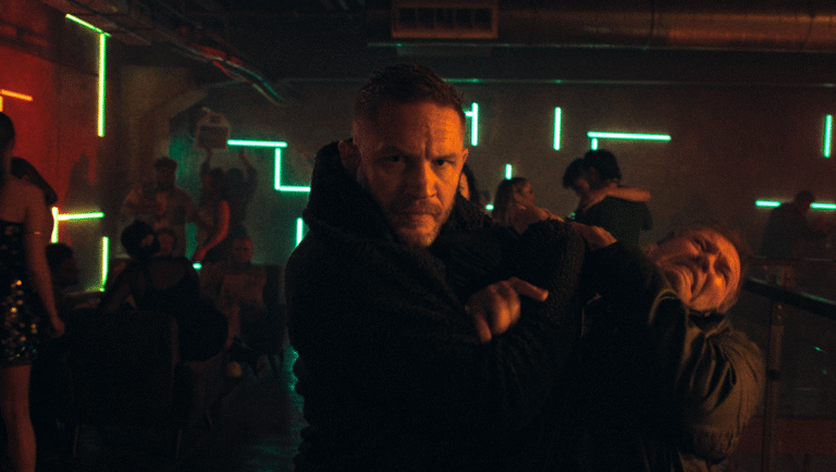 Tom Hardy in a nightclub. Neon lights, dancing people, and dark clothing. Movie scene.