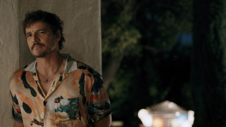 Pedro Pascal portrait. Actor with mustache wearing a colorful shirt and gold necklaces. Celebrity fashion.