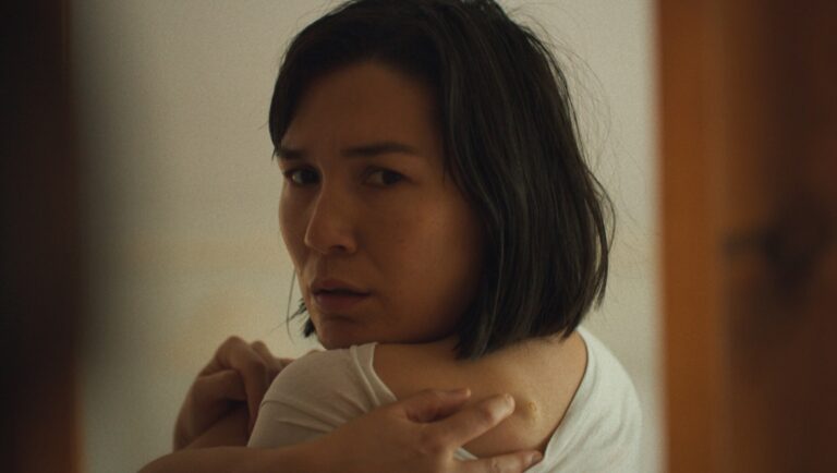 Overlook Film Fest 2025: The True Beauty of Being Bitten by a Tick film still. Woman looks back, concerned.