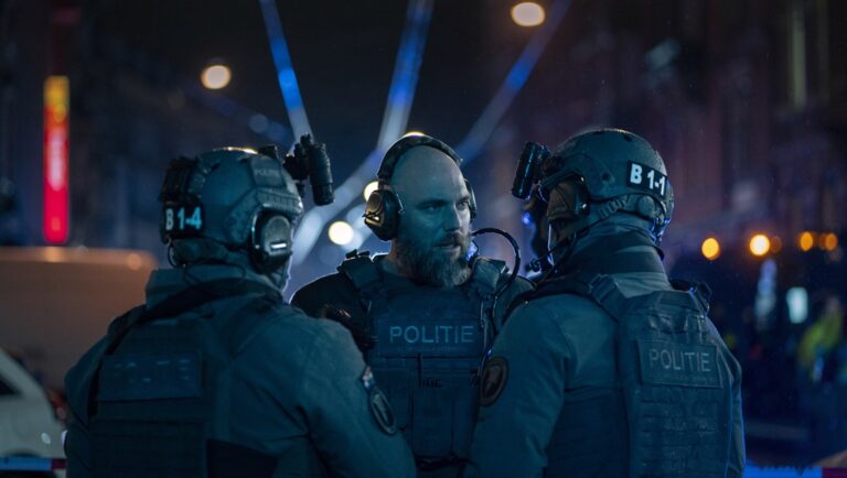 Hostage Netflix series scene: Dutch police tactical unit members in gear confer at night.