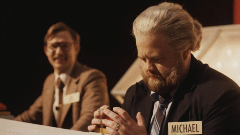 The Luckiest Man in the World movie scene. Michael, with a name tag, sits at a table.