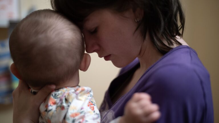 Mother holding baby, forehead to forehead. Young mother with infant. Motherhood, parenting, family love.