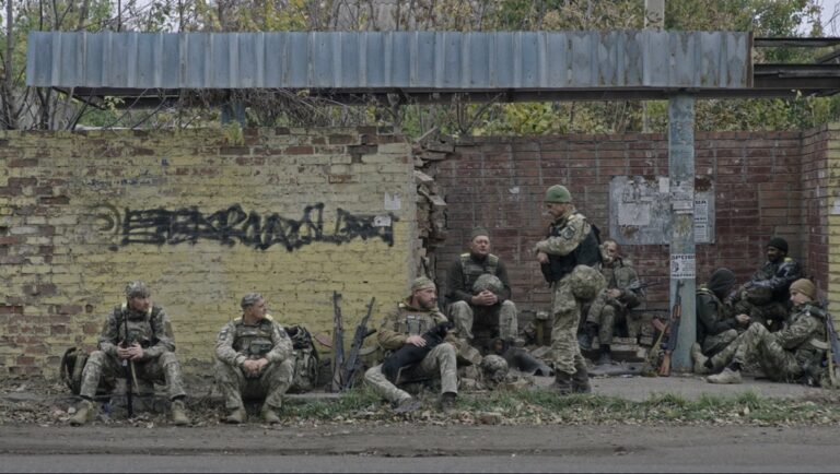 Ukrainian soldiers rest at a damaged bus stop. War in Ukraine. Military personnel.